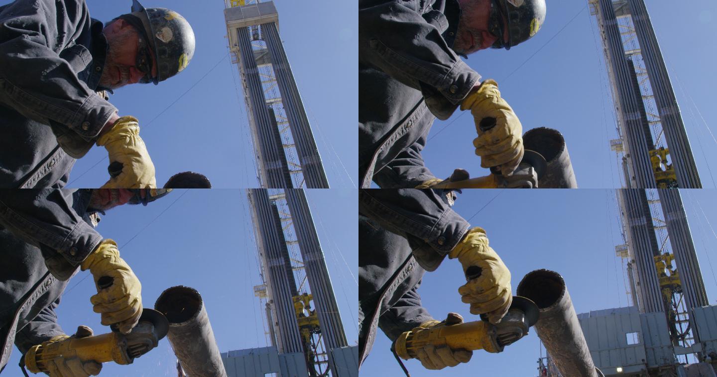 一名男性油田工人在井架旁打磨和锉削金属管