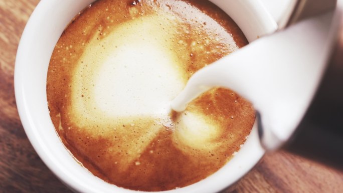 把一大杯蒸牛奶倒进咖啡里做卡布奇诺