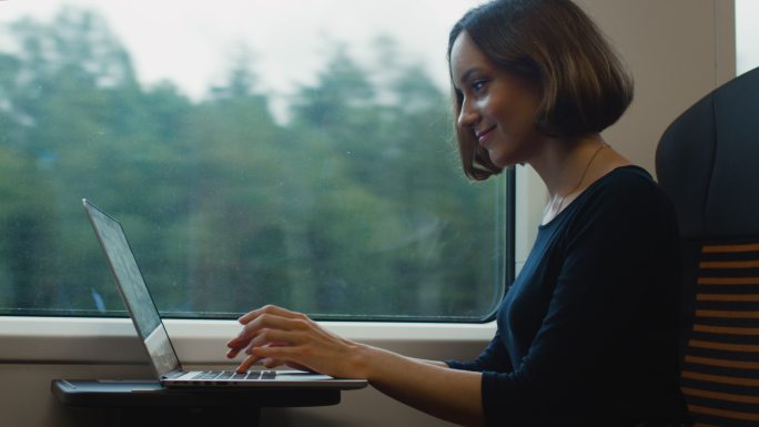 在火车上用笔记本电脑工作的女人。