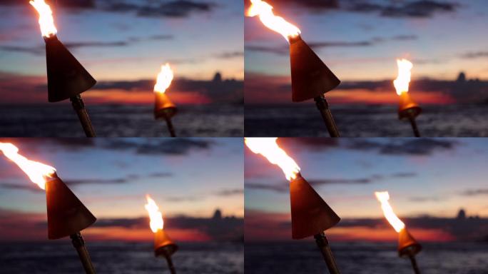 日落时分热带海滩上的火炬火焰
