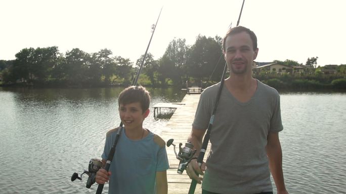 爸爸和儿子带着鱼竿去池塘钓鱼
