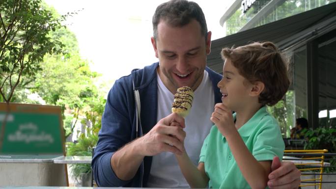 儿子在冰淇淋店和爸爸分享冰棒