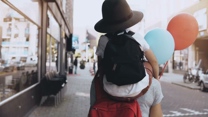 母亲和儿子戴着帽子背着背包一起走在街上