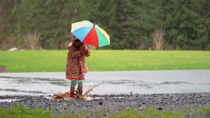 小女孩打着伞在雨中玩耍
