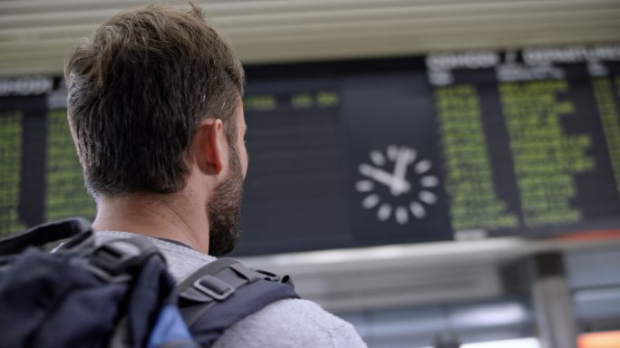男乘客在机场看航班信息显示屏