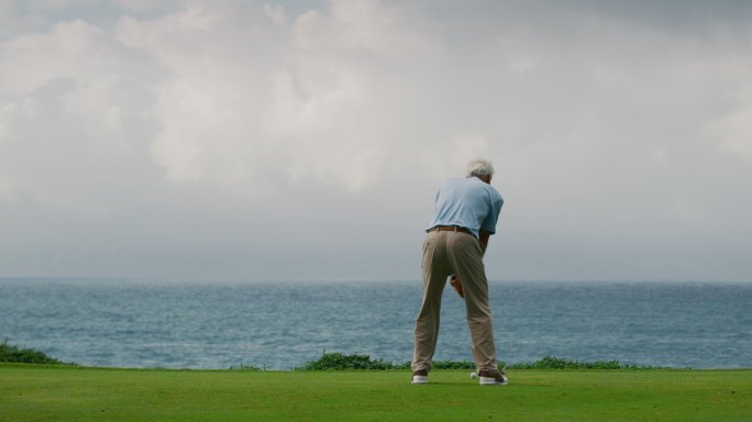 一个老年男子在漂亮的高尔夫球场上挥杆
