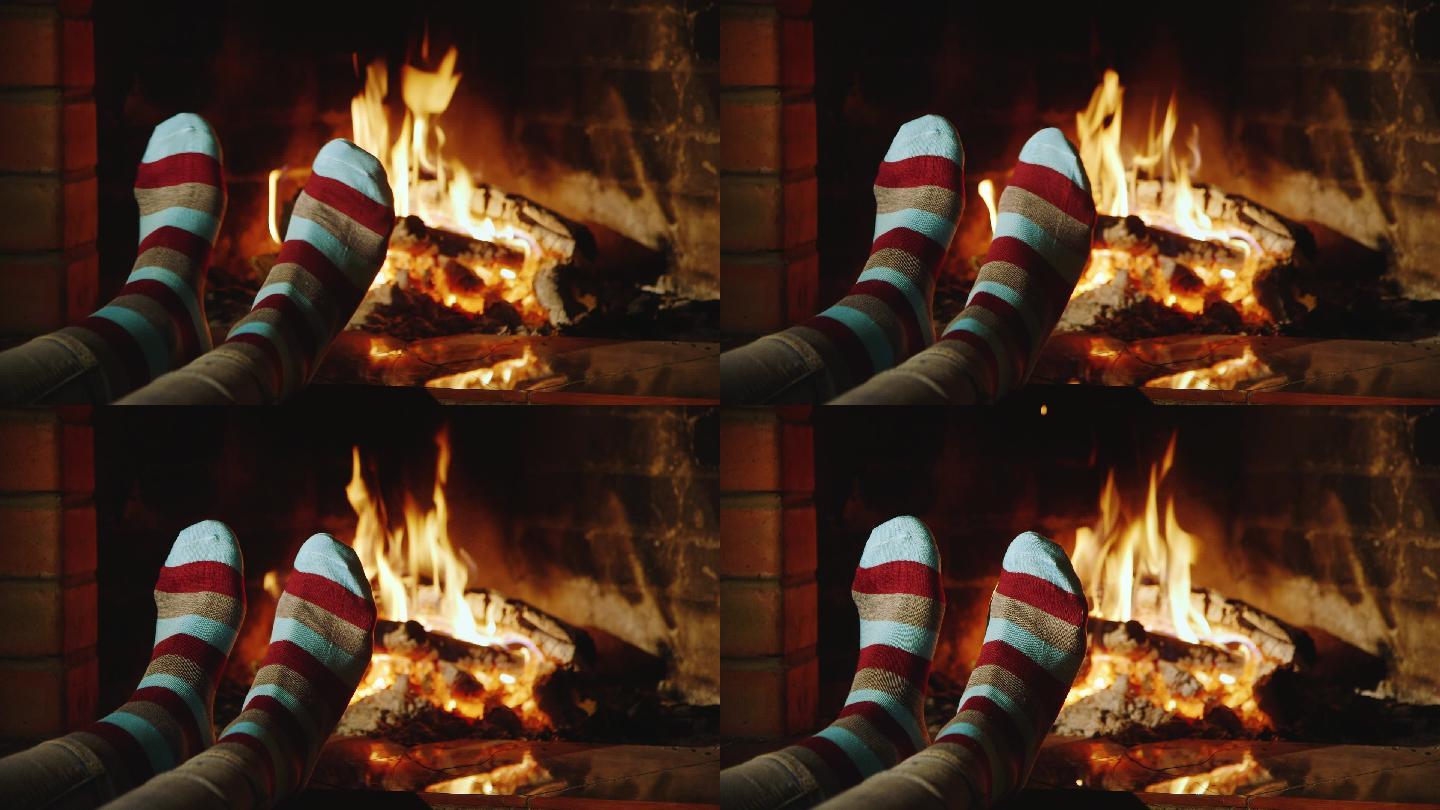 在燃烧的壁炉背景上穿袜子的脚