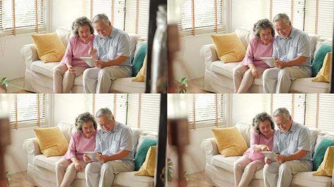 老年夫妇坐在沙发上用平板电脑聊天微笑