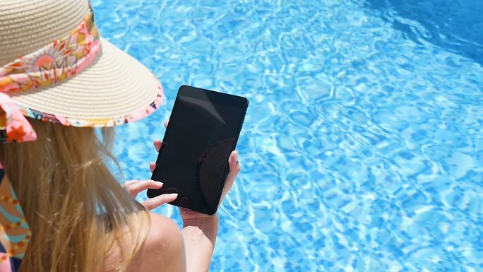 女人在泳池边使用平板电脑