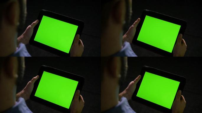 手持黑色背景绿屏平板电脑的人
