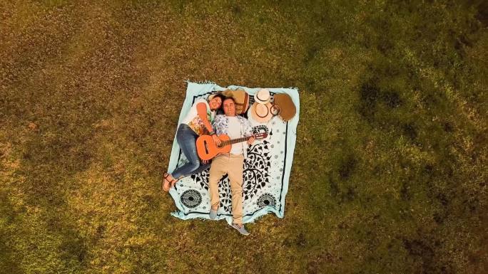 一对夫妇躺在草地上弹奏吉他看着天空