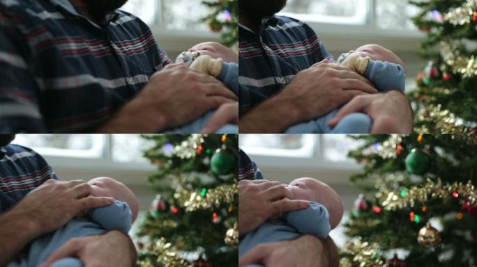 爸爸在圣诞树旁摇着小婴儿