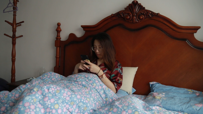 女孩躺床玩手机