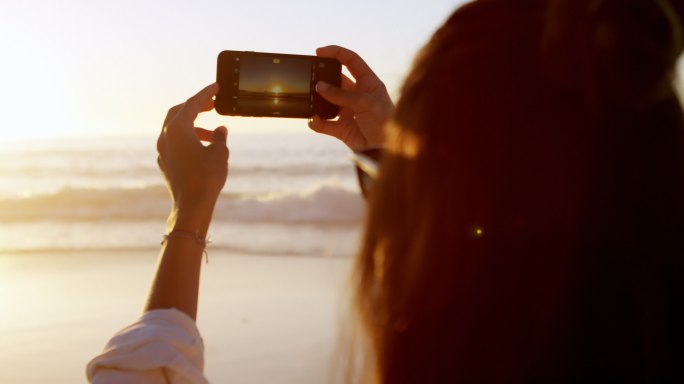 在海滩用手机拍照的女人