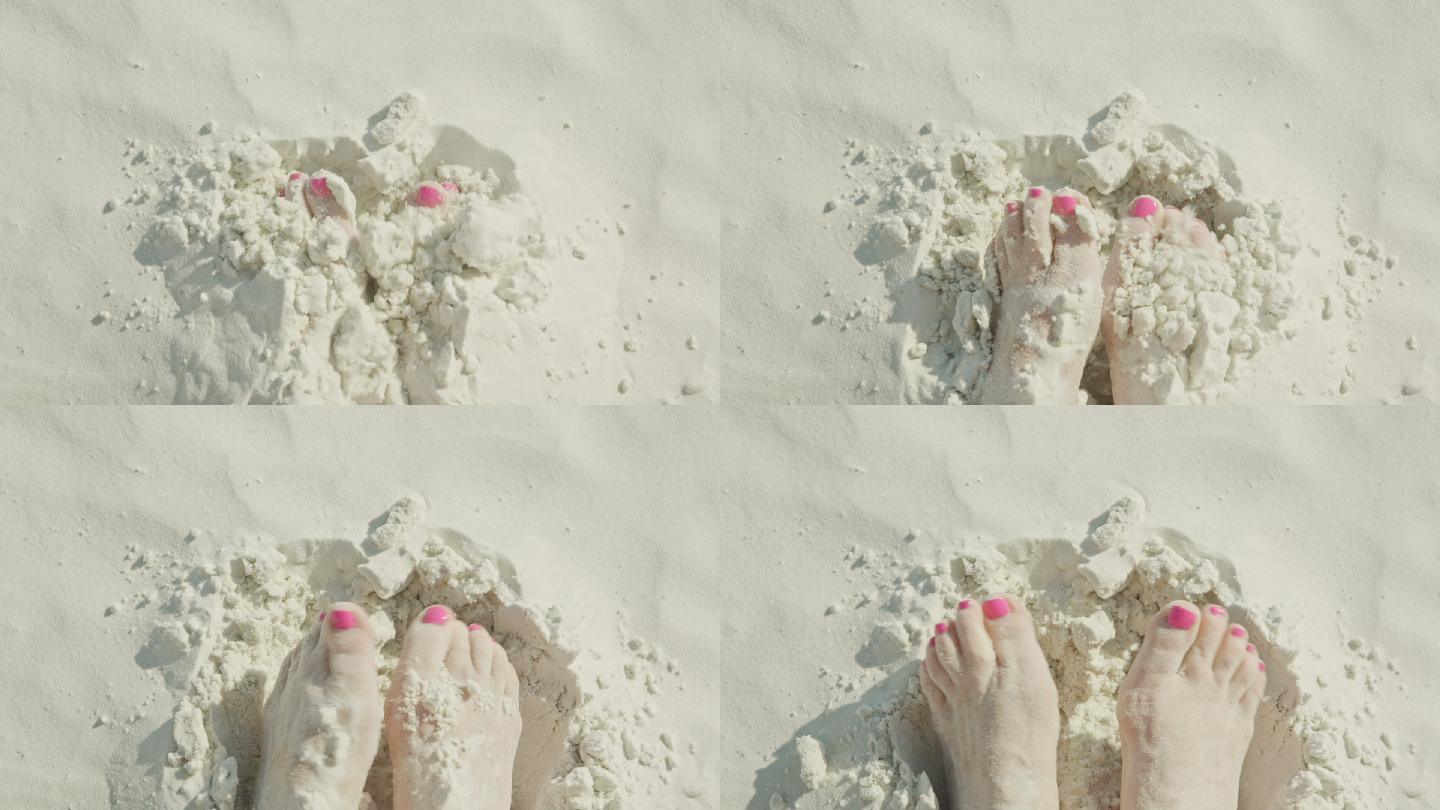 女人的脚埋在纯白的沙滩上