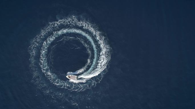 一条船在形成波浪的圆圈中行驶的鸟瞰图。