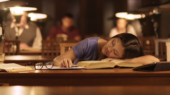 一位女性在图书馆看书时睡着了