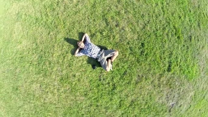 一个人躺在草地上，镜头拉远。
