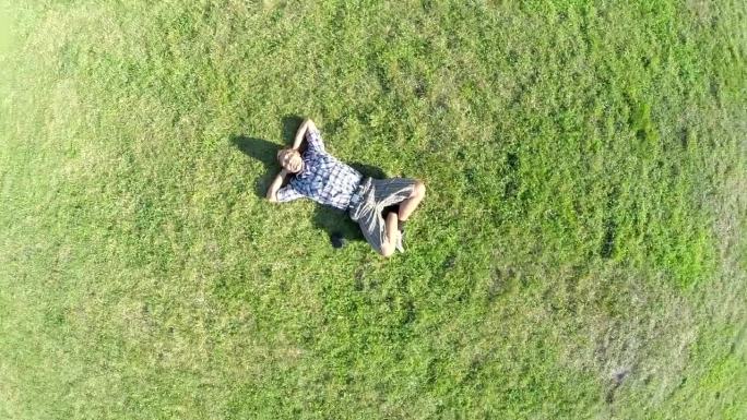 一个人躺在草地上，镜头拉远。