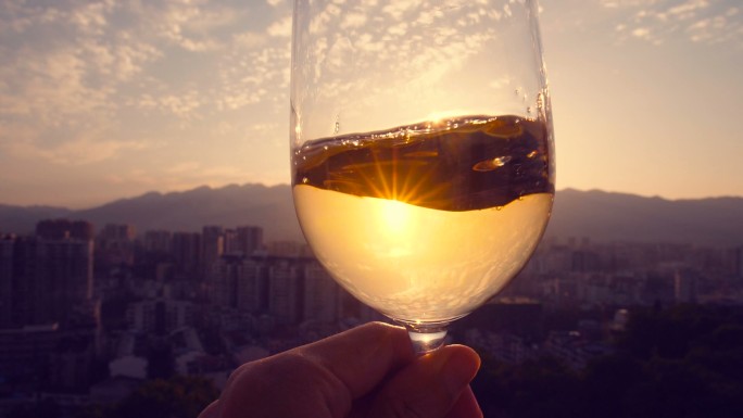 夕阳下手持白葡萄酒