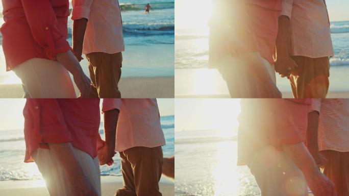 在沙滩上手牵手散步的夫妇