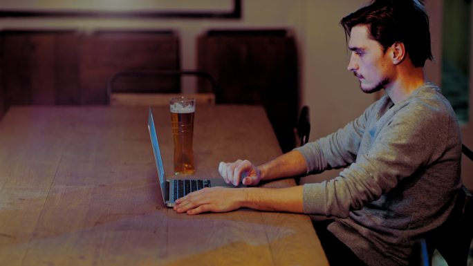 一个年轻人在酒吧里用笔记本电脑