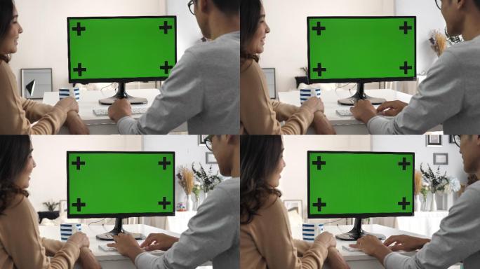 两个人一起使用绿屏电脑并说话