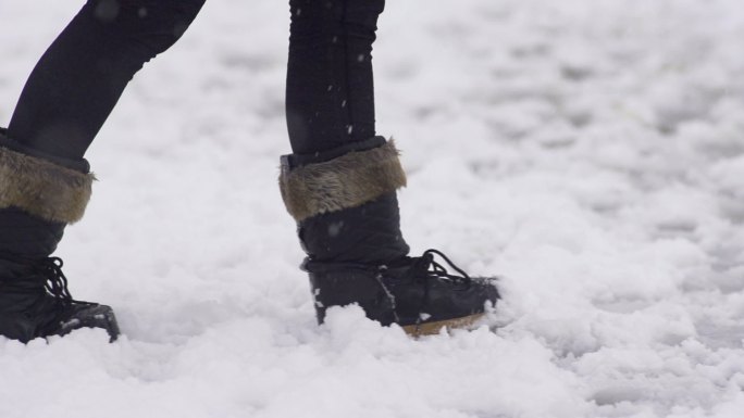 一穿着雪地靴穿行在雪地里的女子