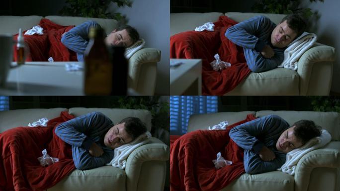 一个男子躺在沙发上裹着毯子咳嗽