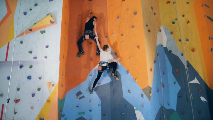 两个人正在爬人工攀岩墙