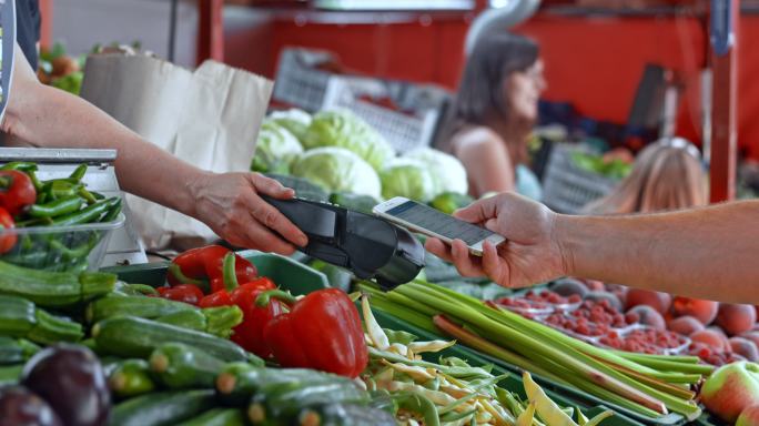 在市场上用手机购买蔬菜的人