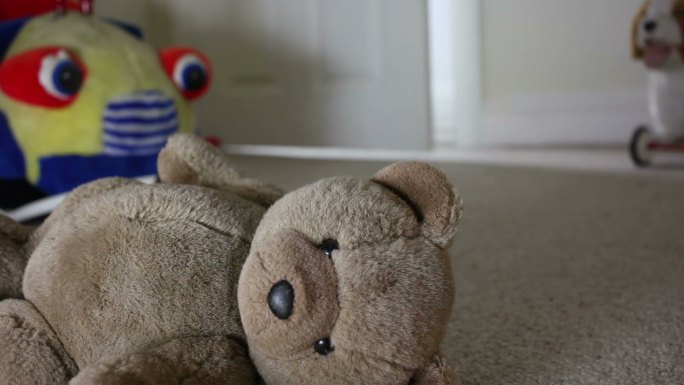 一个孩子的泰迪熊被丢弃在地板上。