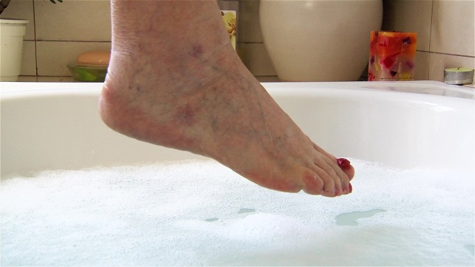 老妇人的脚放在浴缸边上