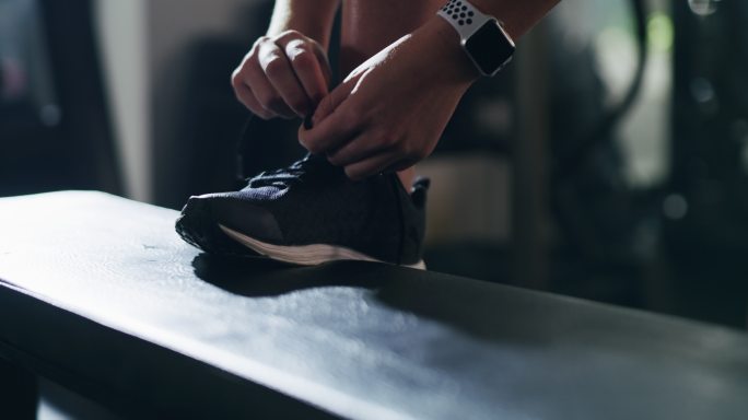 在系鞋带的运动员脚特写鞋子健身健身房年轻