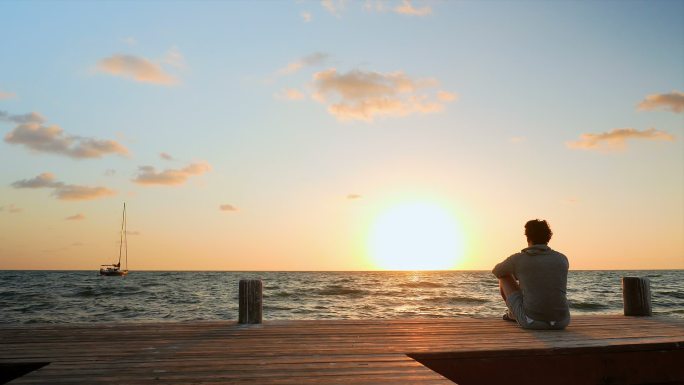 坐在海边看日落的男人