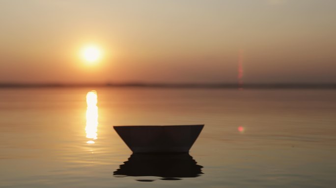 在海水或湖水中放开一艘纸船的剪影