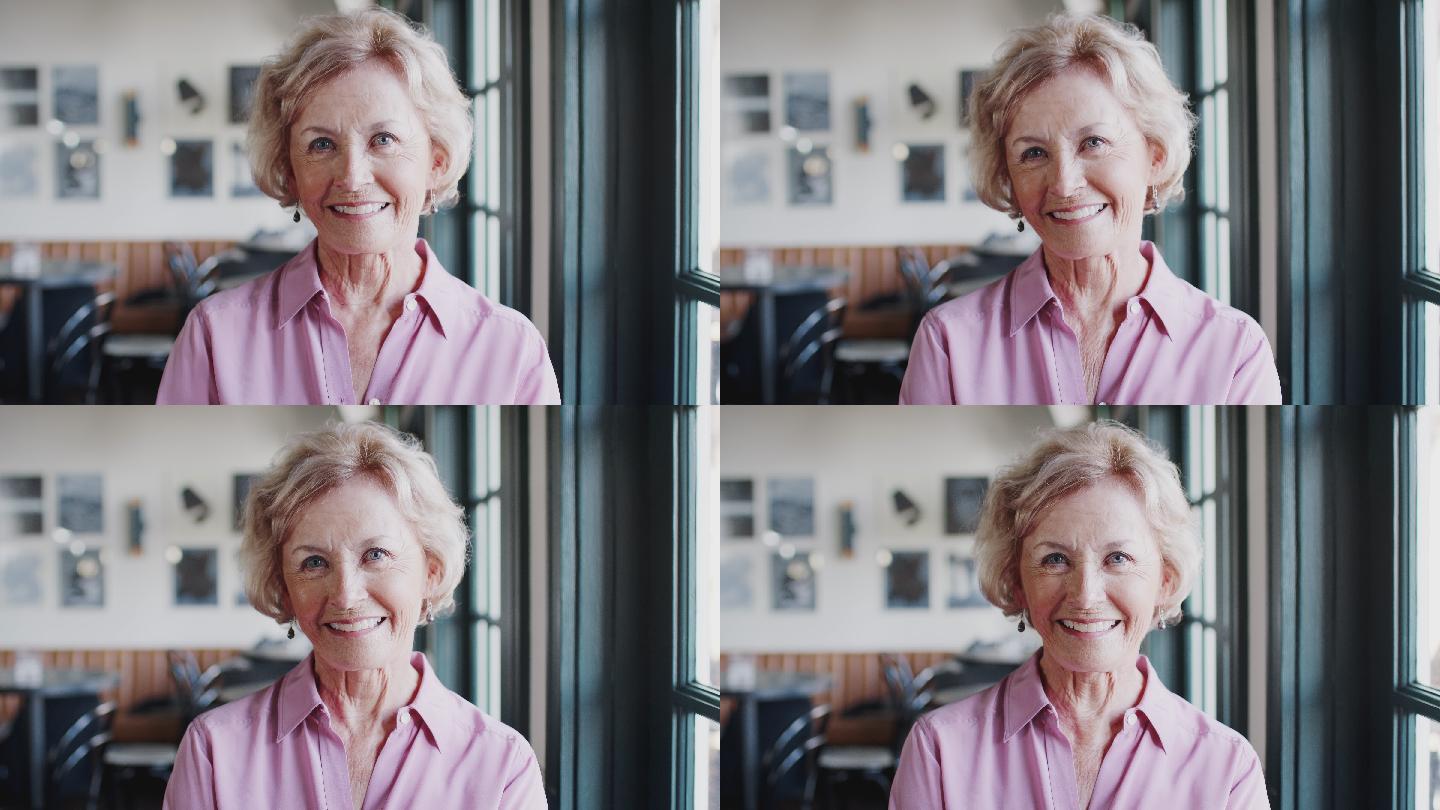 微笑的老妇人坐在餐厅里的画像