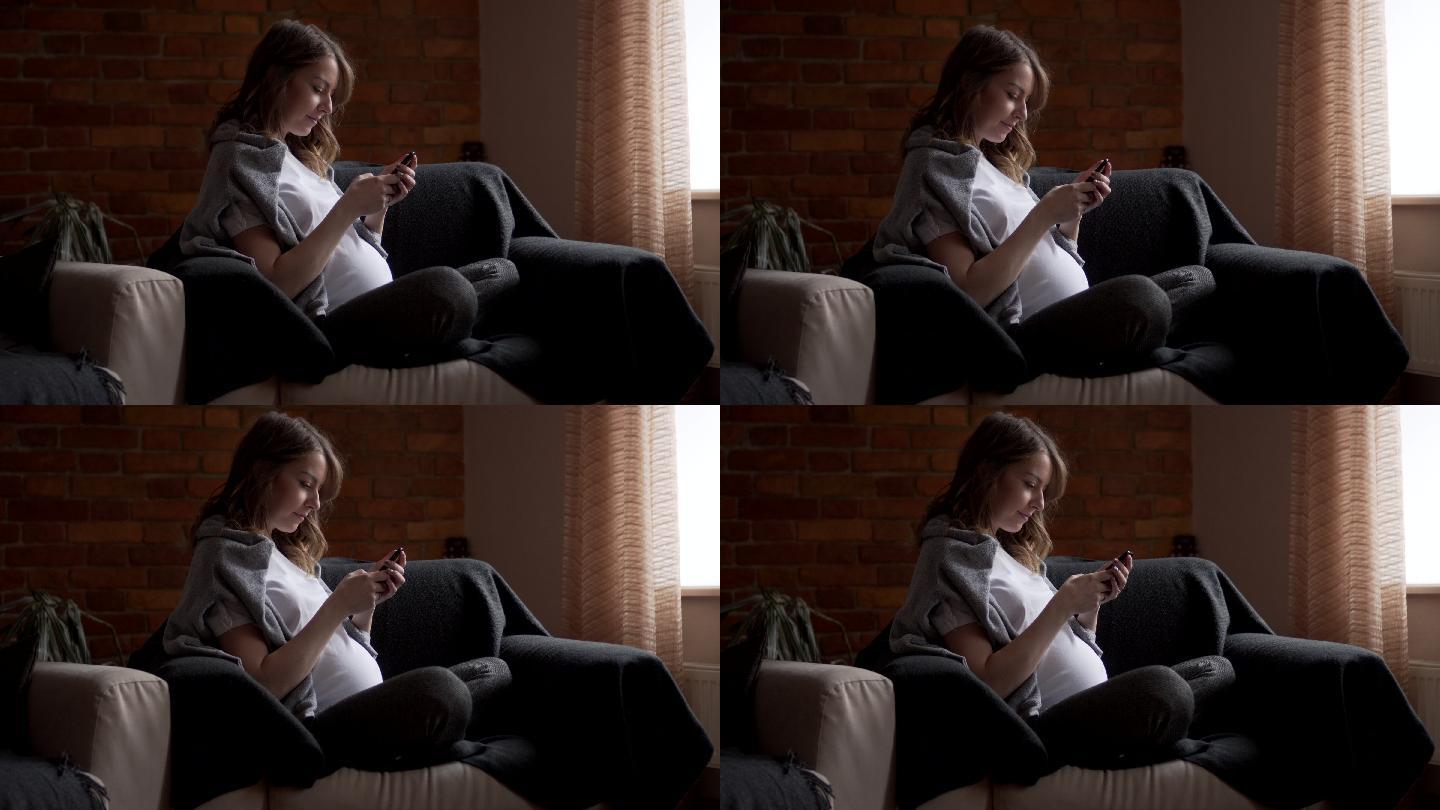 孕妇在沙发上使用手机发短信