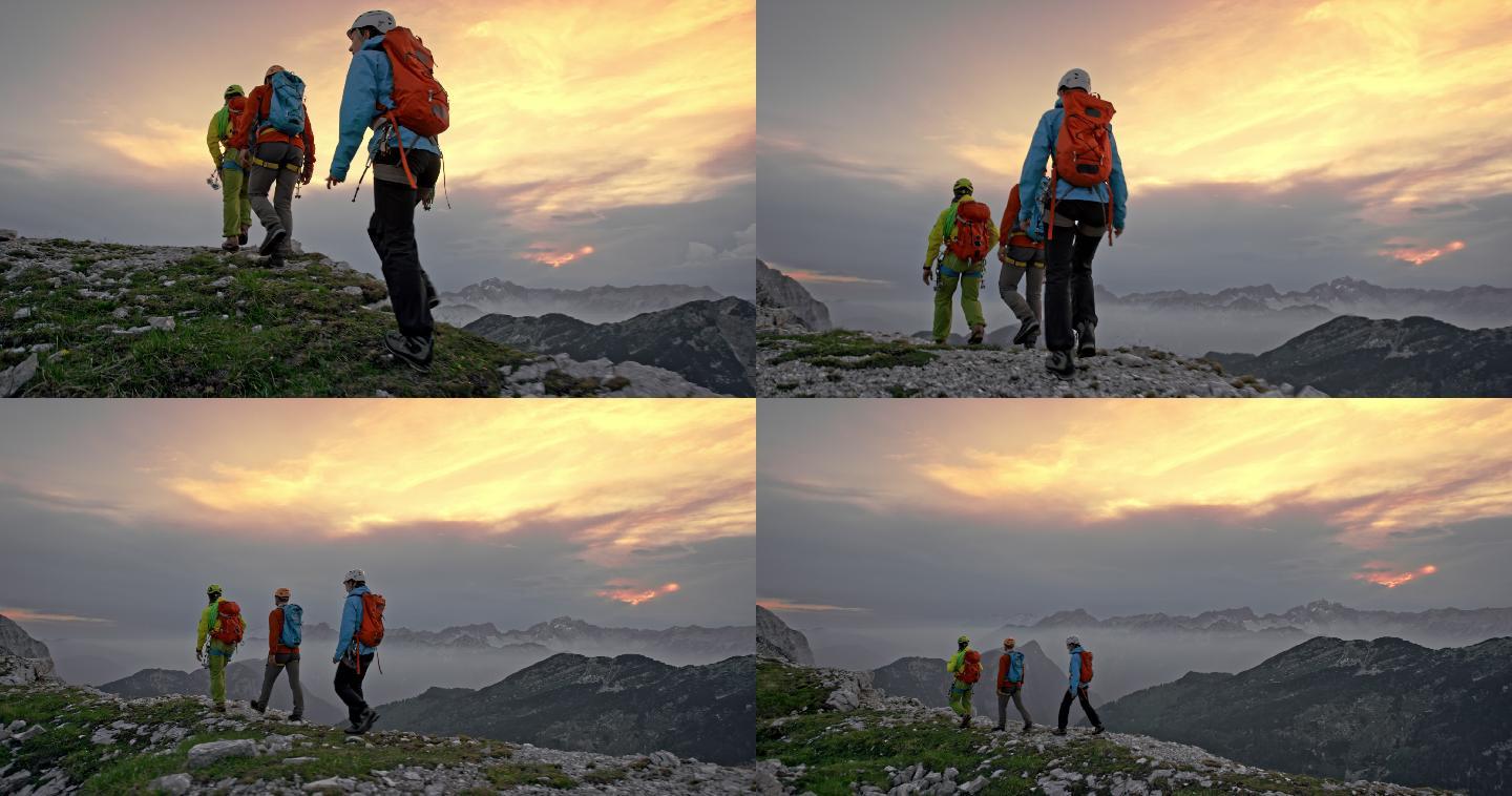 日落时分三个登山者在山脊上行走
