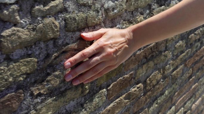 女人用手在古老的红砖墙上滑动