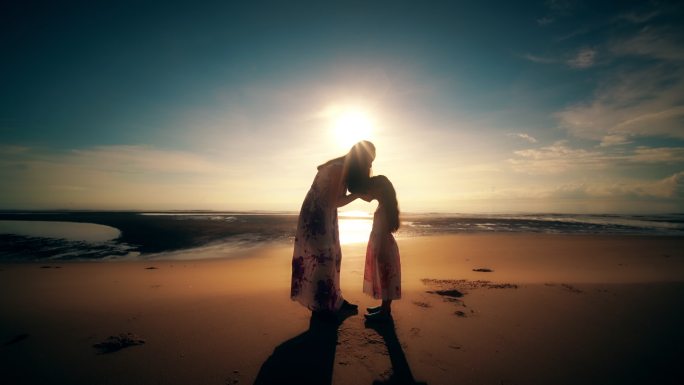 夕阳下海滩上拥抱的母女