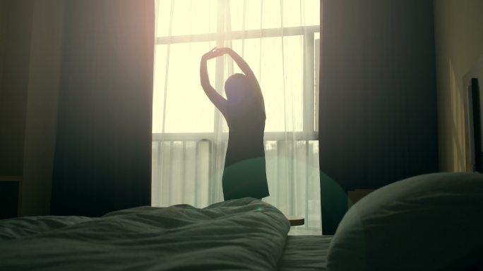 早晨女人在窗边伸腰