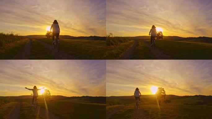 落日时分，一个女人骑着自行车伸出双臂