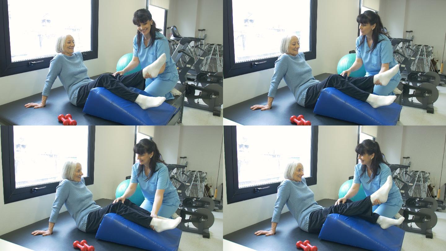 护士协助老年妇女进行腿部锻炼