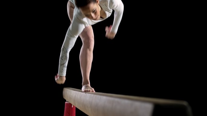 女子体操运动员在平衡木上做翻转动作