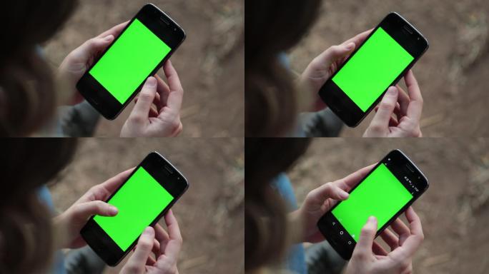 手持绿色屏幕手机的人。