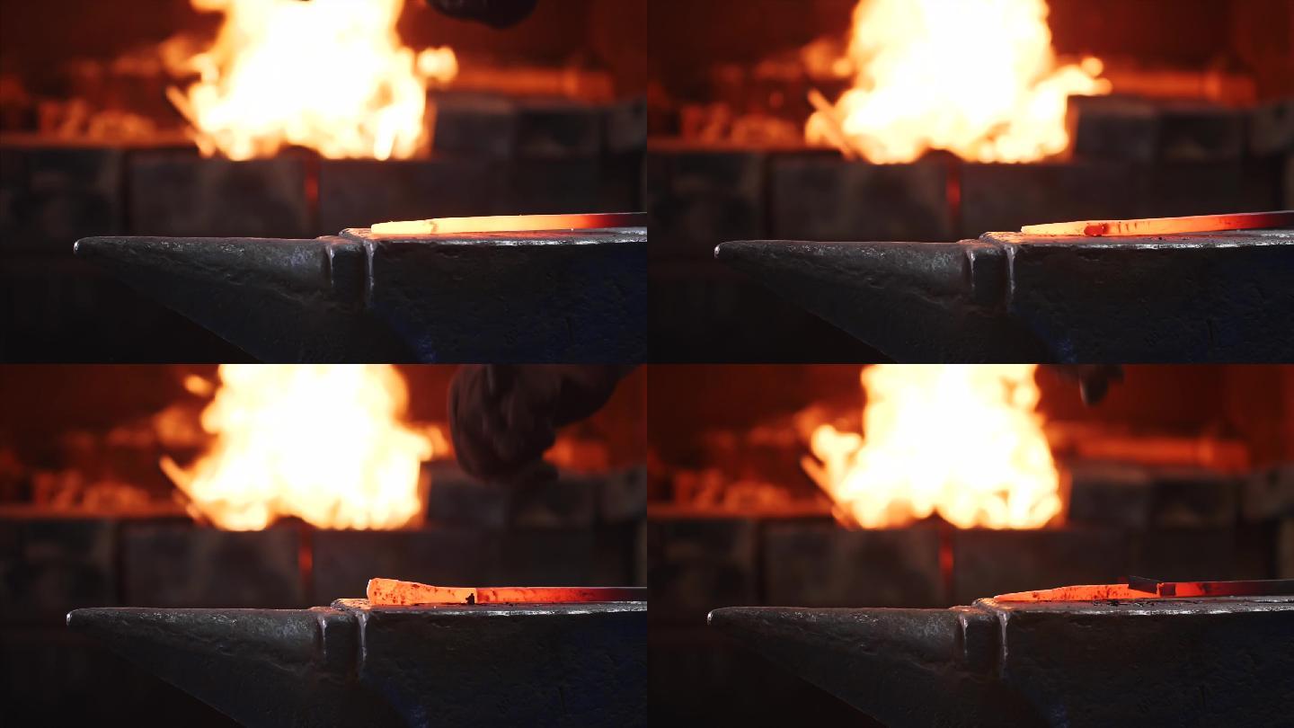 铁匠用大铁锤敲击铁砧上的热金属棒。