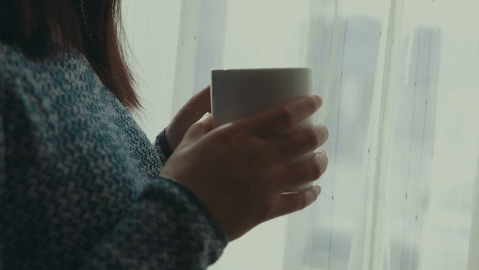 靠近窗户端着咖啡的女人特写镜头