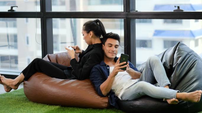 坐在豆包上玩手机的年轻夫妇