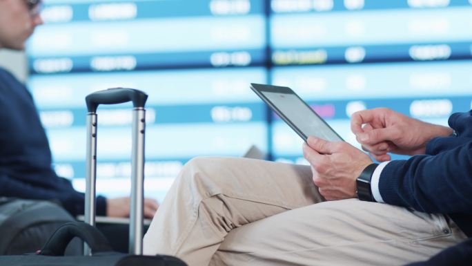 在机场候机室候机时使用平板电脑的男子